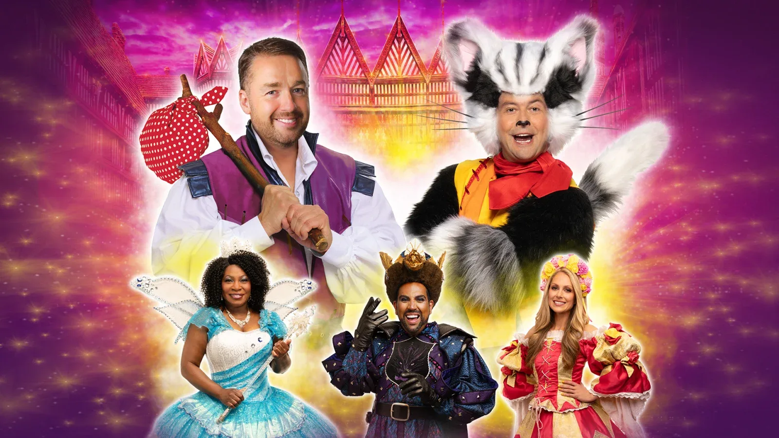 The cast of the Manchester panto at the Opera House in costume, including the cat, in front of a glowing fairytale city