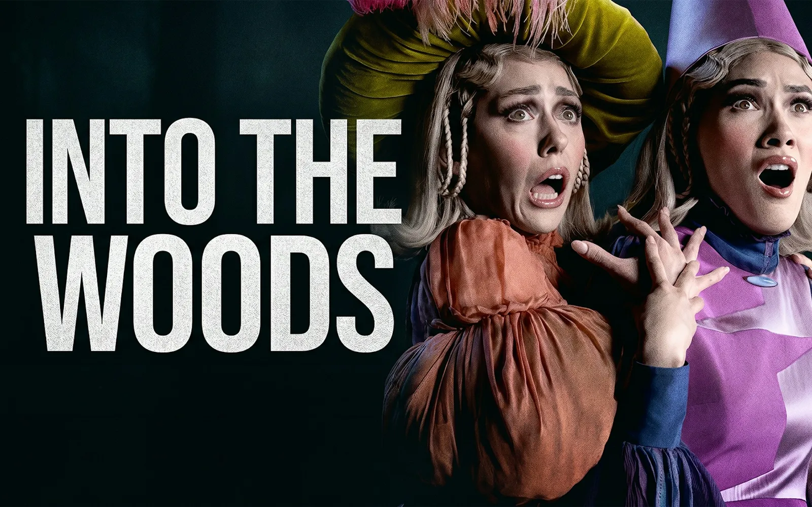 Two startled women in fairytale costume, the nearer in a towering wig, gasp on a dark backdrop beside bold white lettering