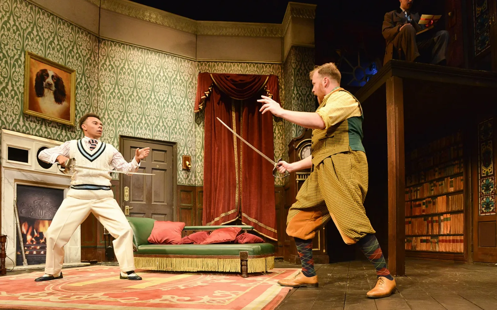 Two actors in period costume fence with swords in a green-wallpapered drawing room with a dog portrait on the wall