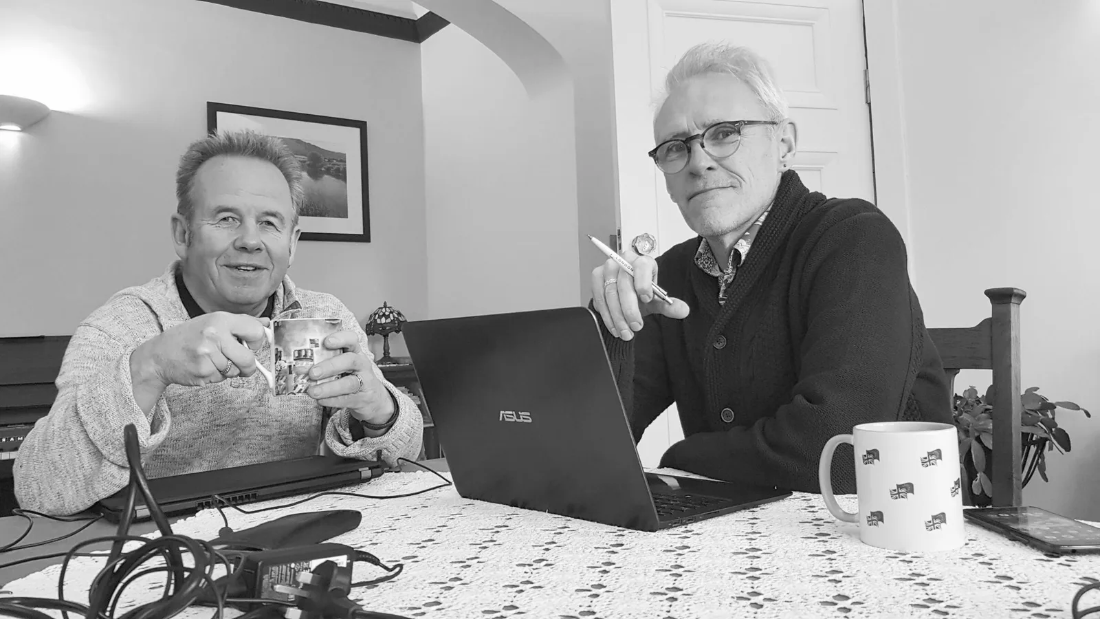 Co-writers Jimmy Rae and Peter Davies of Under the Mersey Moon seated together at a table with laptops